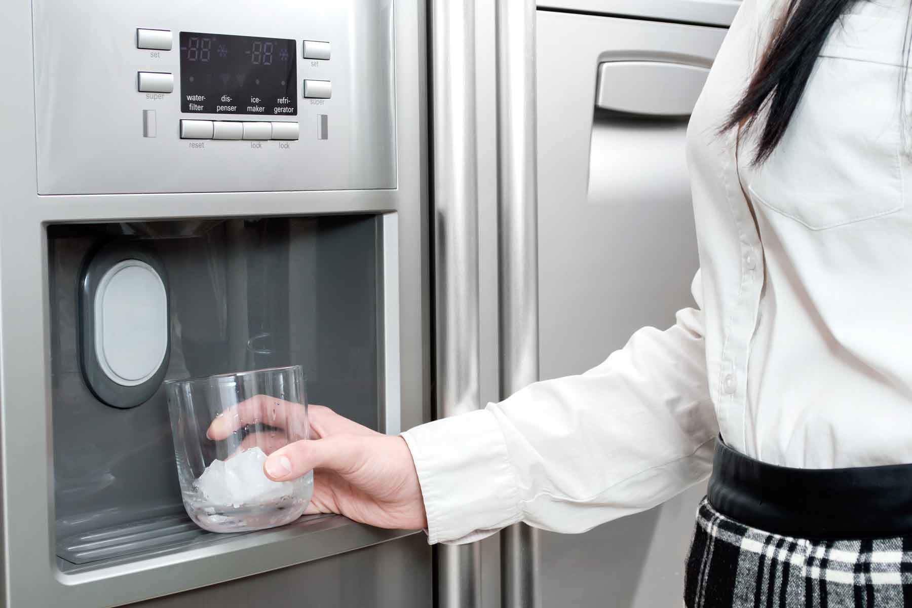 homeguide-woman-getting-ice-cubes-from-icemaker-in-refrigerator-door